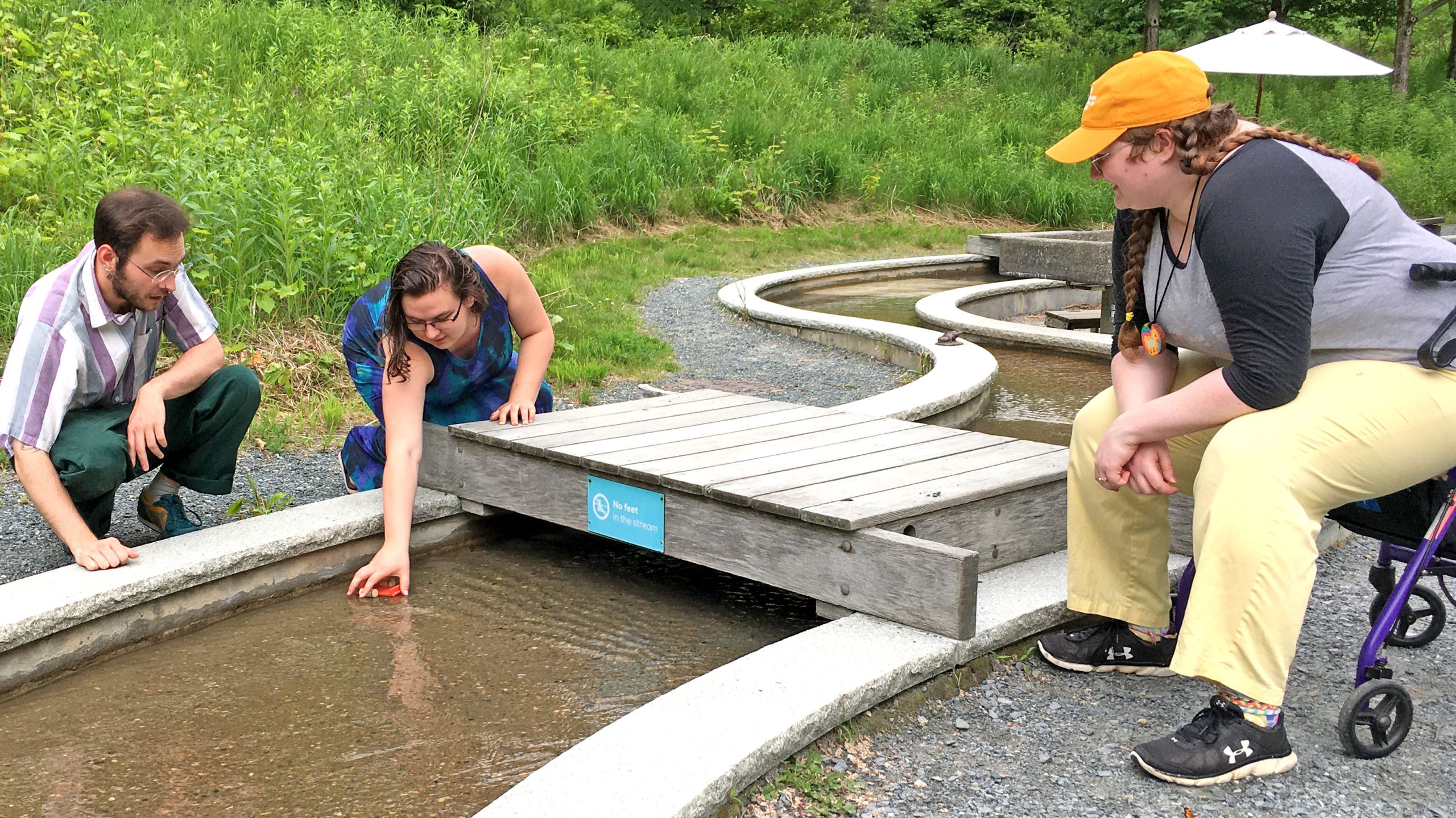 Three visitors test a cork boat in the Science Park rill