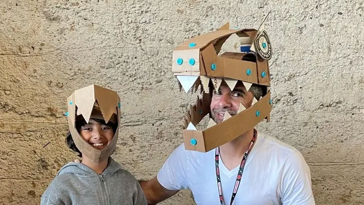 A child and an adult wearing toothed cardboard masks