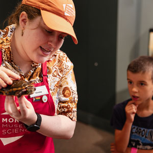 A Montshire Explainer shows a painted turtle to a group of visitors