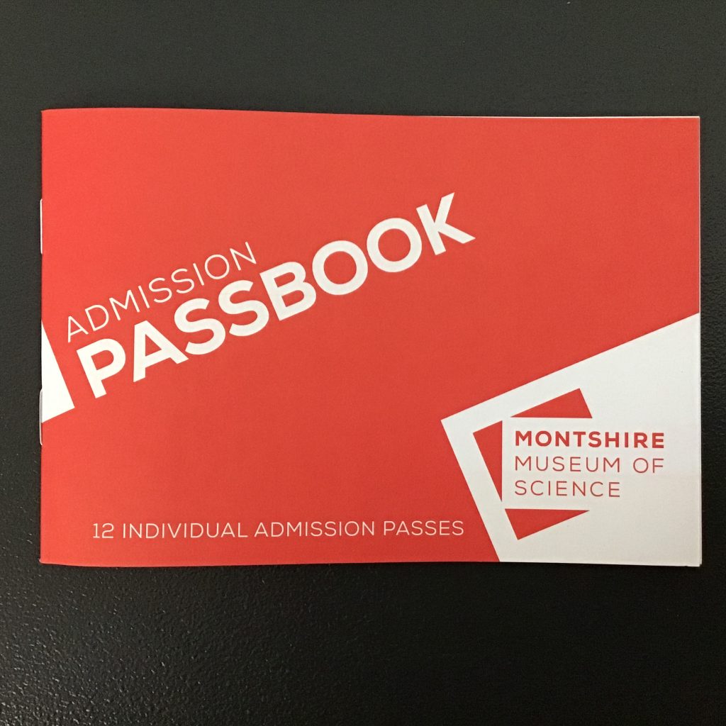 Photo of a Montshire passbook. A red paper book with the word "passbook" on the cover, and a Montshire logo in the bottom right corner.