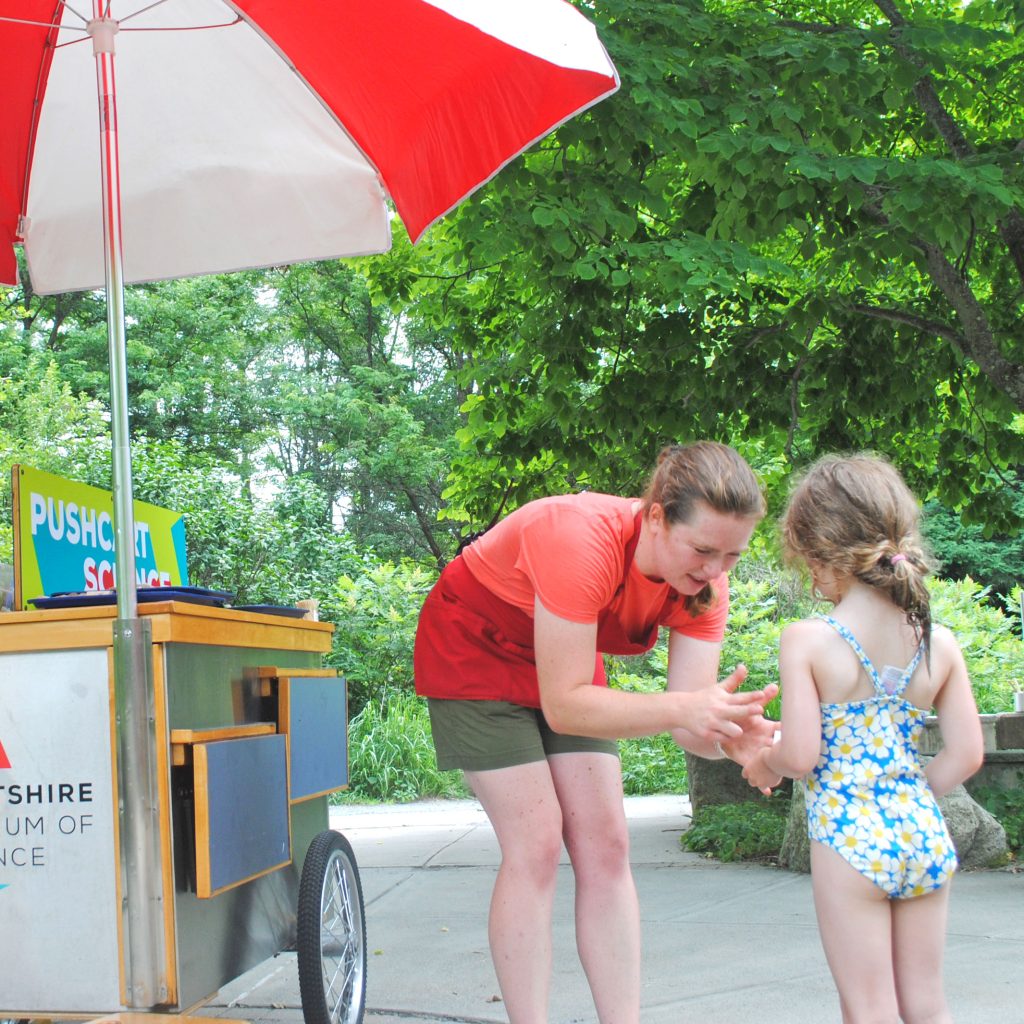 An explainer helps a young visitor make a cork boat